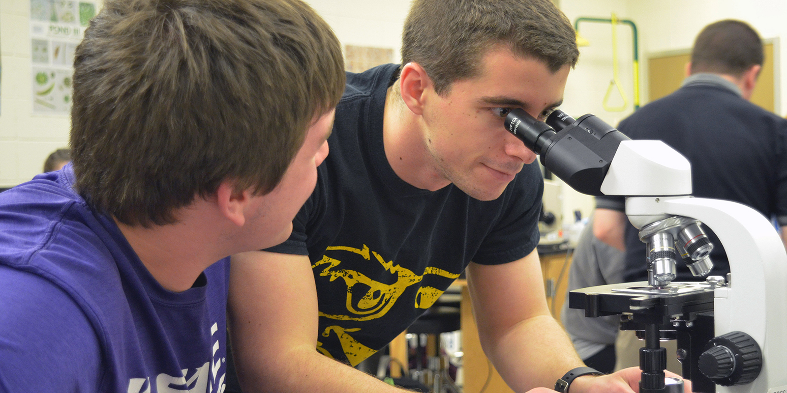 Two students looking at a microscope.